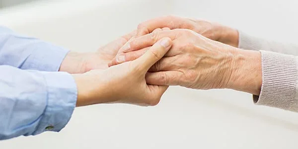 Persona giovane che prende le mani di una persona anziana