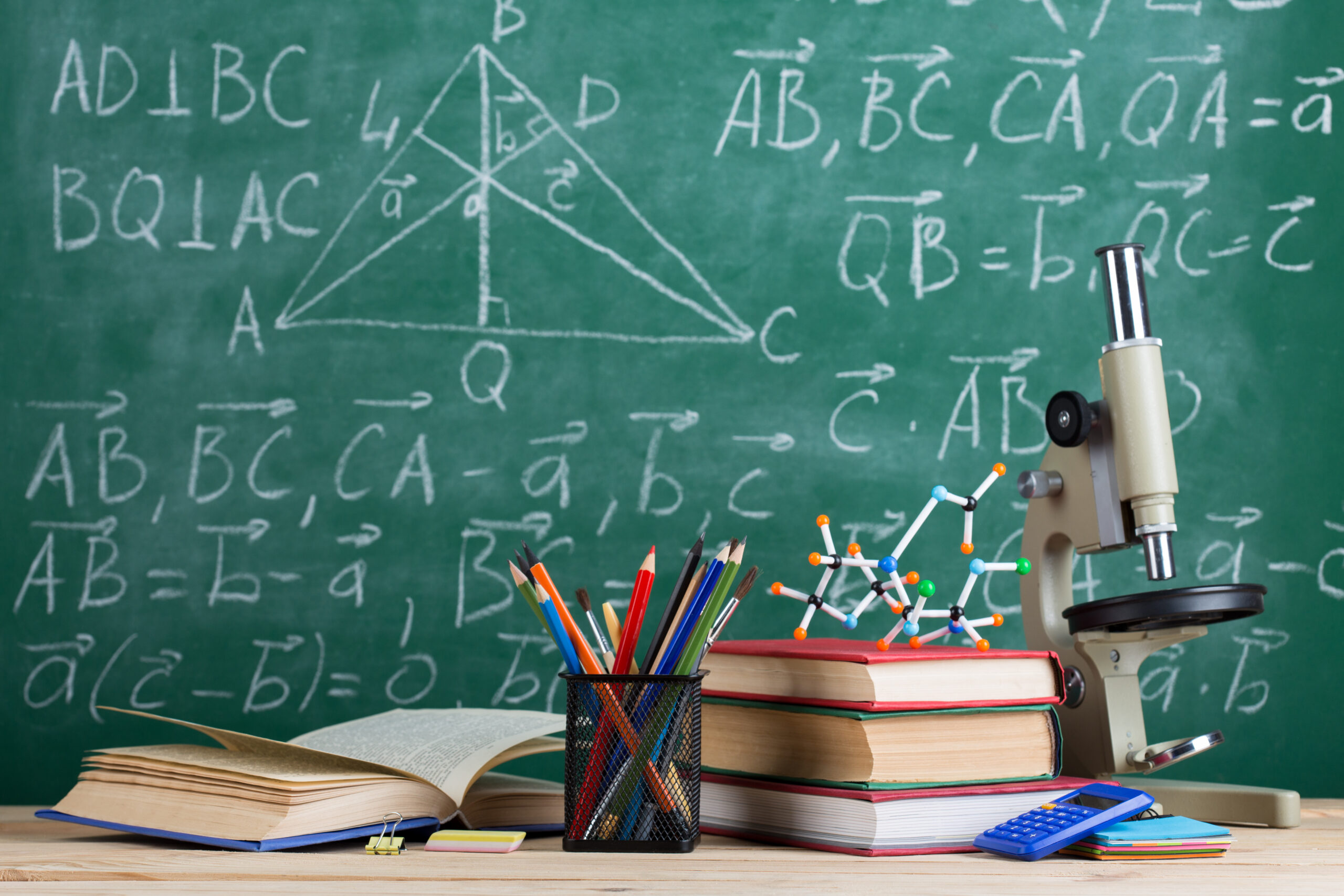 Un tavolo con un microscopio, alcuni libri e matite, simboli di ricerca e apprendimento.